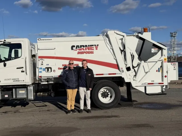 Chris and George Carney standing in front of a Carney Disposal trash truck