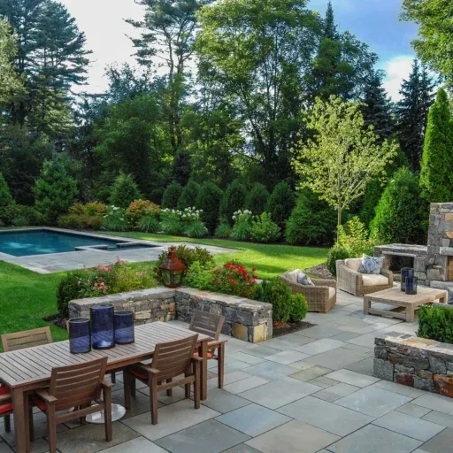This Dover stone patio creates an inviting backyard gathering space with natural masonry, layered planting, and timeless residential landscape design.