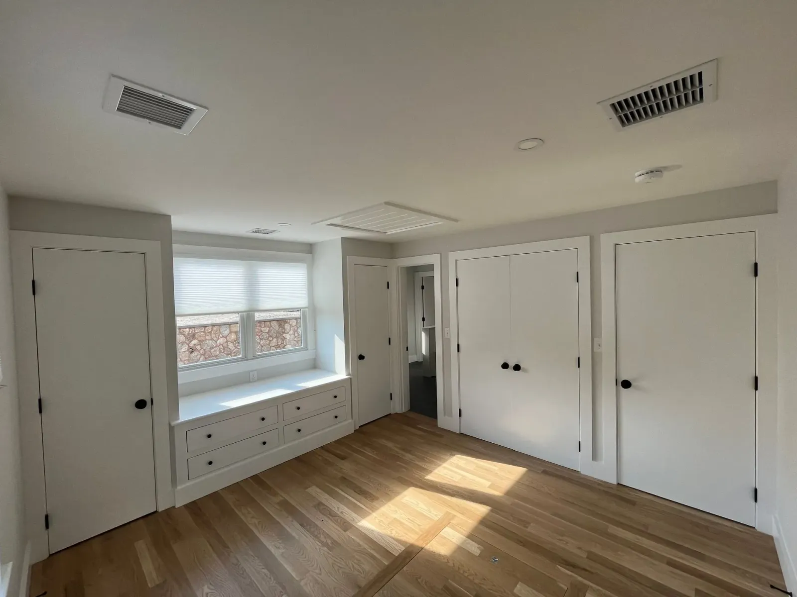 A large empty room with hardwood floors and white doors