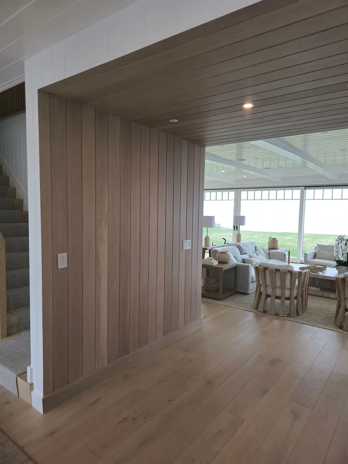 A living room with wood paneling and a staircase.