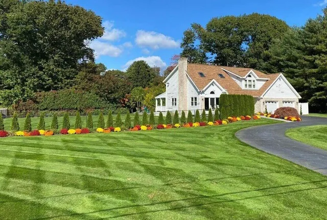 A house with a driveway and lawn in the background.