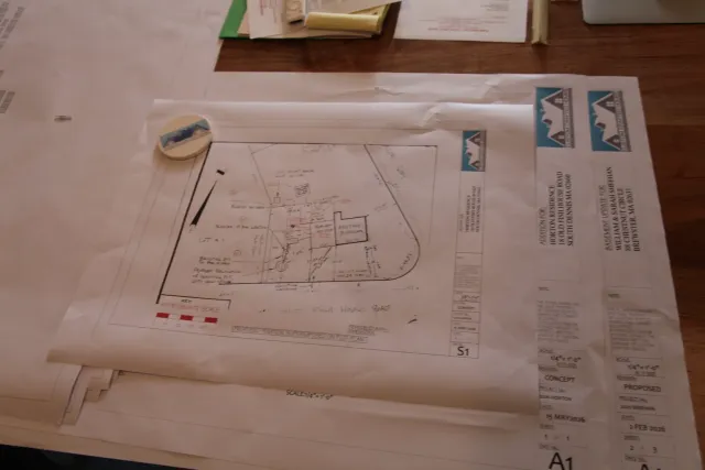 Architectural site plan and blueprints spread across a table