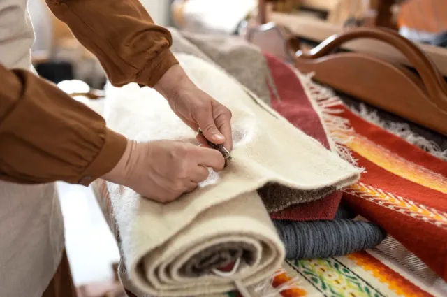 A person is rolling a rug on a table.