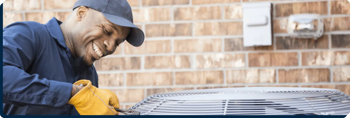 worker smiling fixing HVAC unit