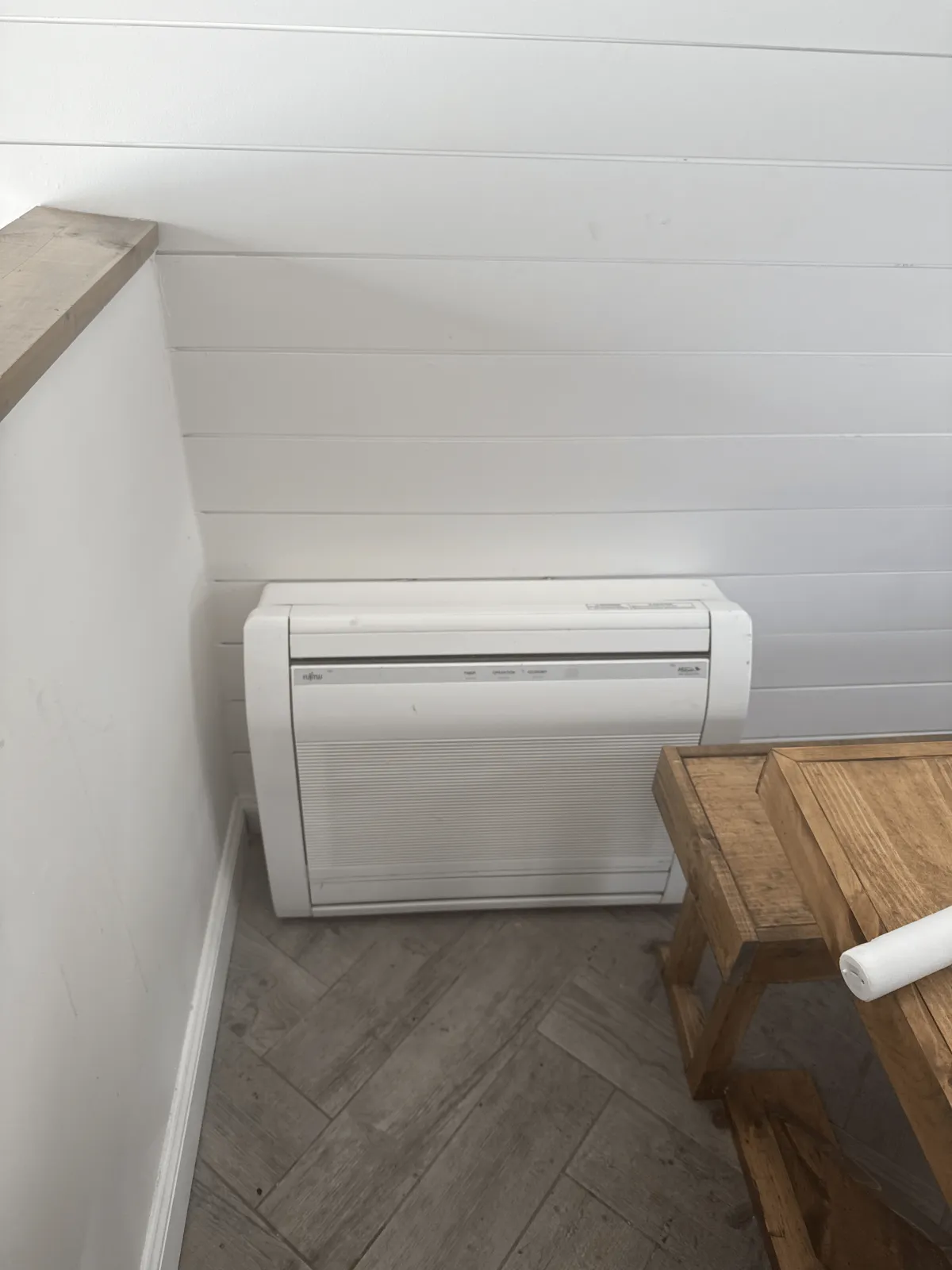 White Fujitsu ductless mini-split indoor unit mounted on basement wall with shiplap ceiling