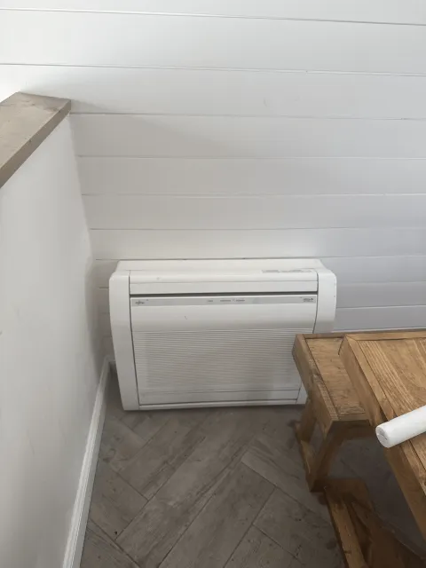 White Fujitsu ductless mini-split indoor unit mounted on basement wall with shiplap ceiling