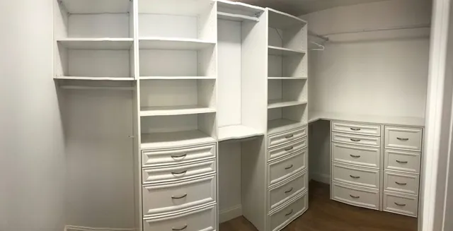 A custom built-in closet with organized shelves, drawers and polished hardware
