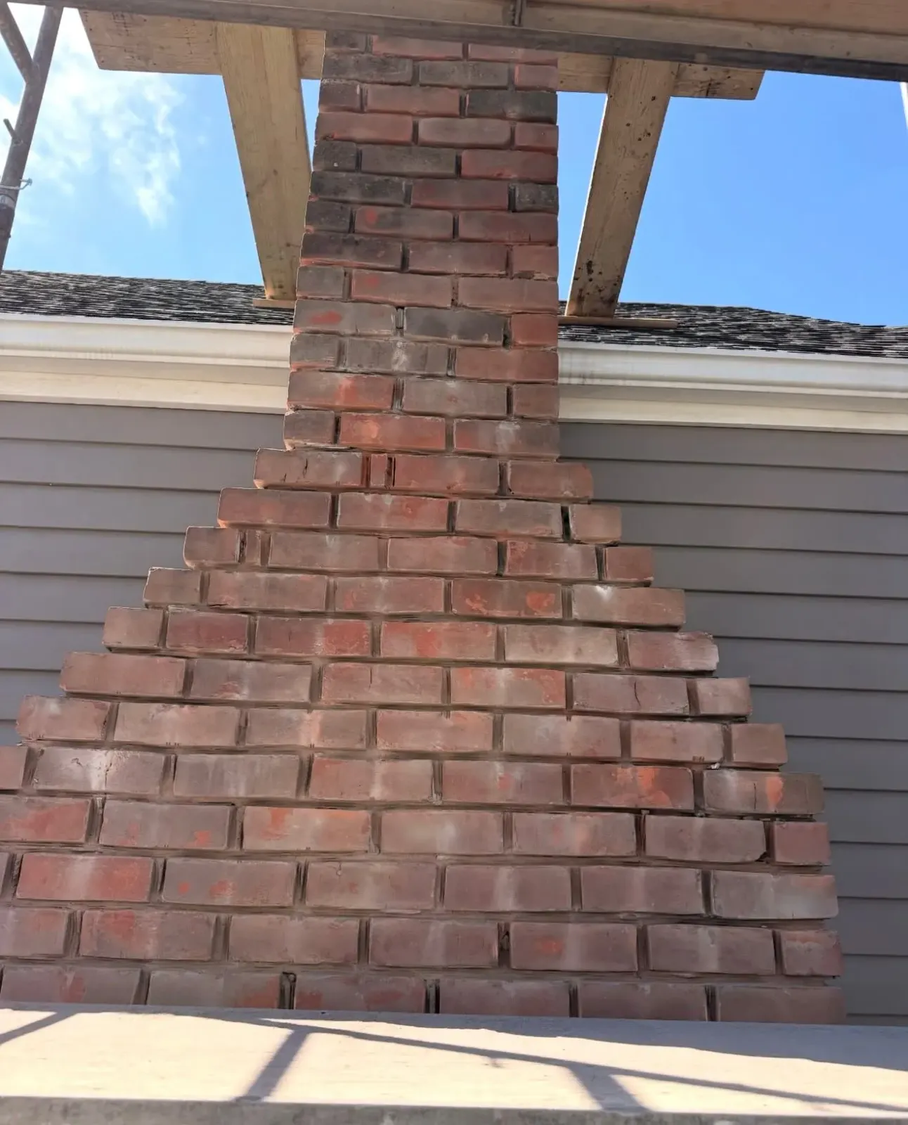 Newly laid red brick chimney base with stepped masonry corbel