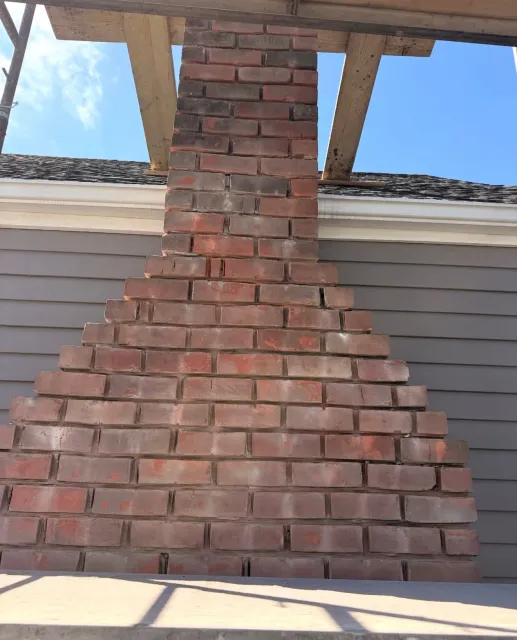Newly laid red brick chimney base with stepped masonry corbel