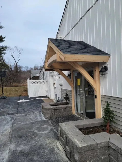 A white building with a wooden canopy over the door.
