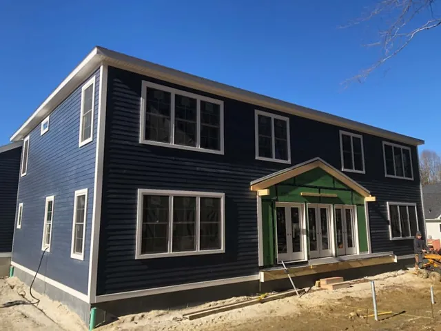 Navy two-story new build with a sheathed rear bump-out and French doors, before the porch was added