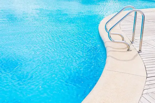 Clean in-ground swimming pool with stainless steel handrails and bright blue water