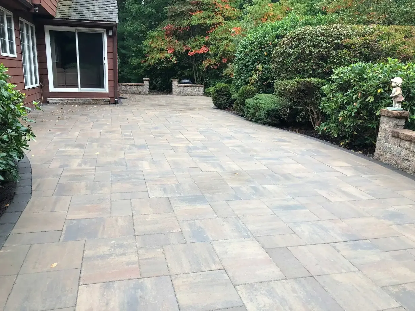 Paver terrace and retaining wall beside a shingled home