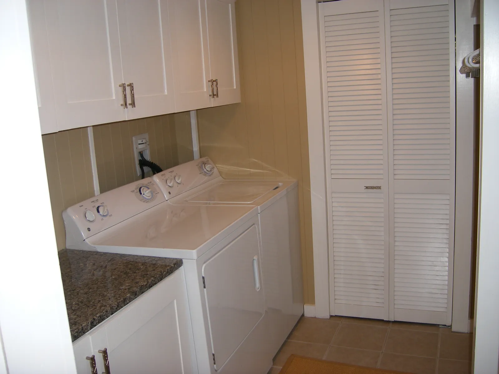 Finished laundry room with cabinetry and stone counter