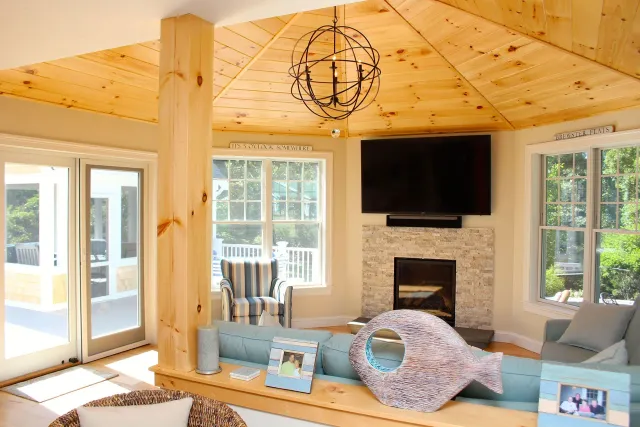 Living room with wooden ceiling, fireplace, and a fish-shaped pillow on a blue sofa.