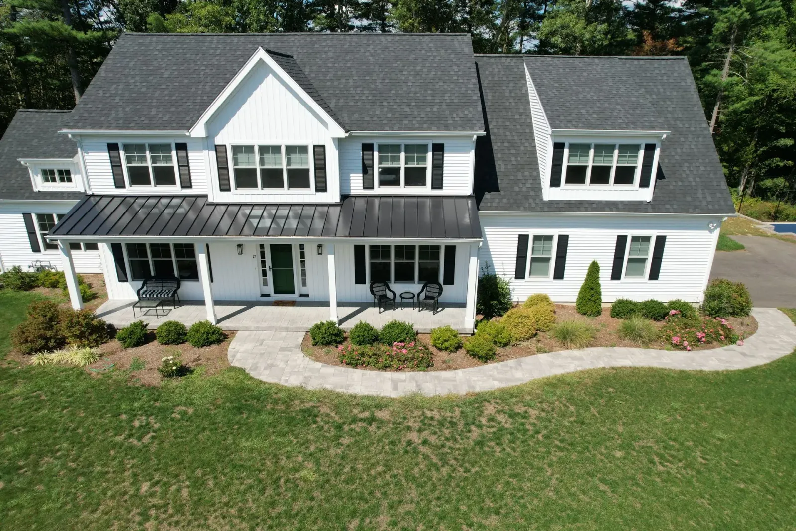 White suburban two-story house with gray roof, front porch, and a large green lawn