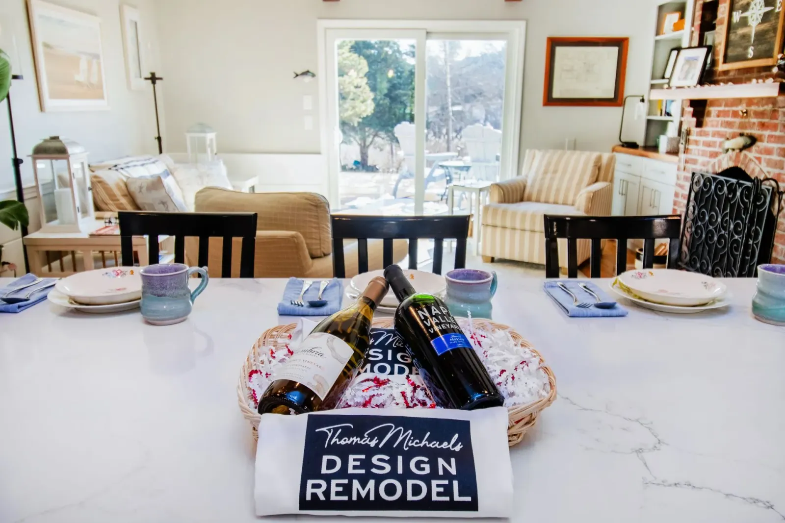 Dining room table set for a meal. Two wine bottles rest on a basket with a
