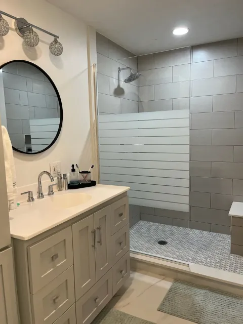 A bathroom with a sink , mirror , and shower.