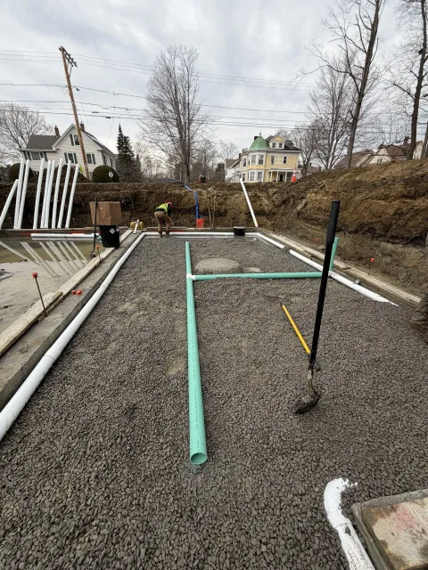 Backyard gravel patio with turquoise frame, black poles, and leafless trees under cloudy sky
