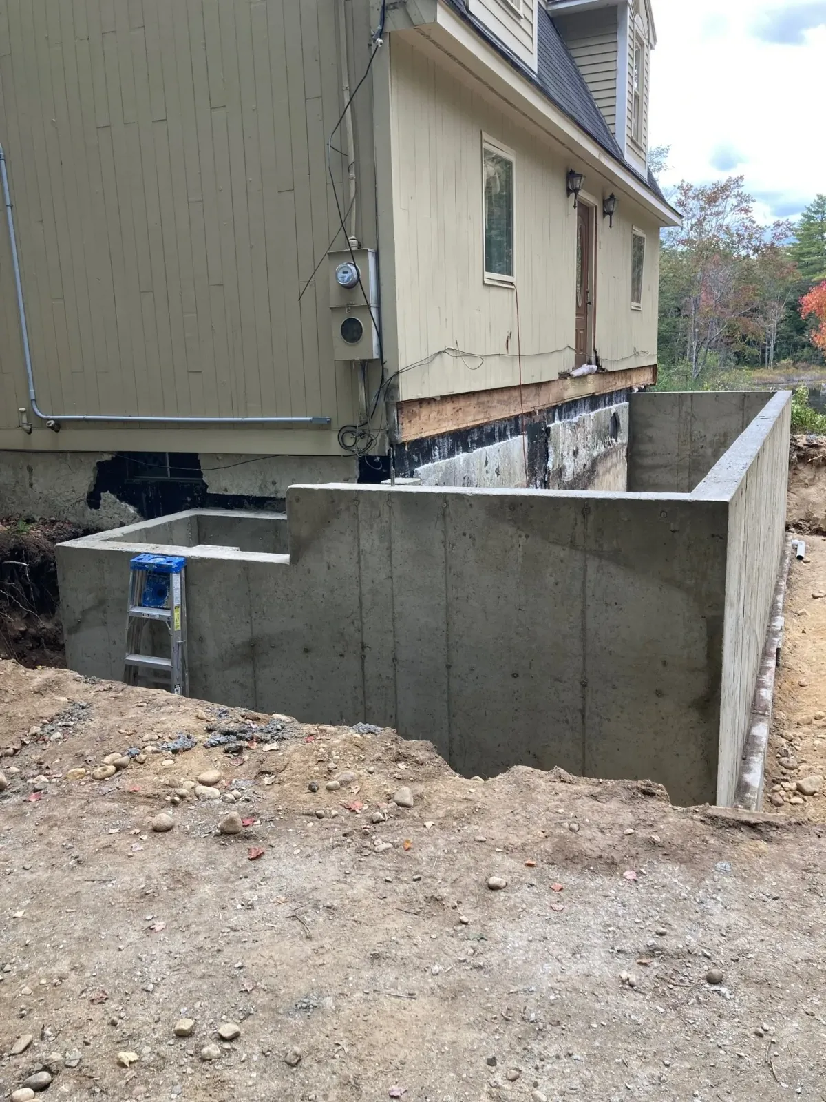 A concrete wall is being built in front of a house.