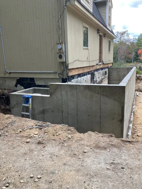 A concrete wall is being built in front of a house.