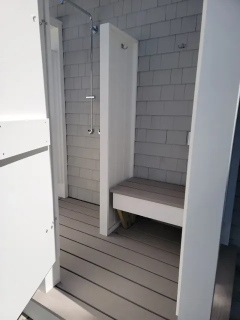 A bathroom with a bench and a shower stall