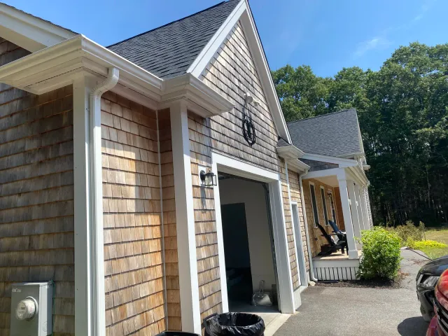 Cedar shingle garage with white gutter and downspout installation