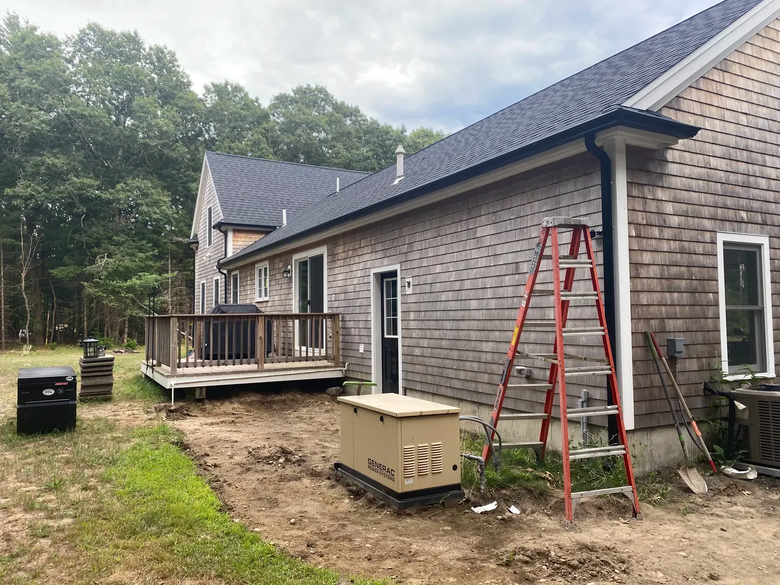 Side yard view of a cedar home with newly installed black gutter system