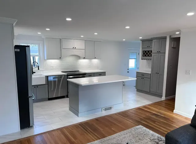 Modern kitchen with gray and white cabinets, stainless steel appliances, and an island.