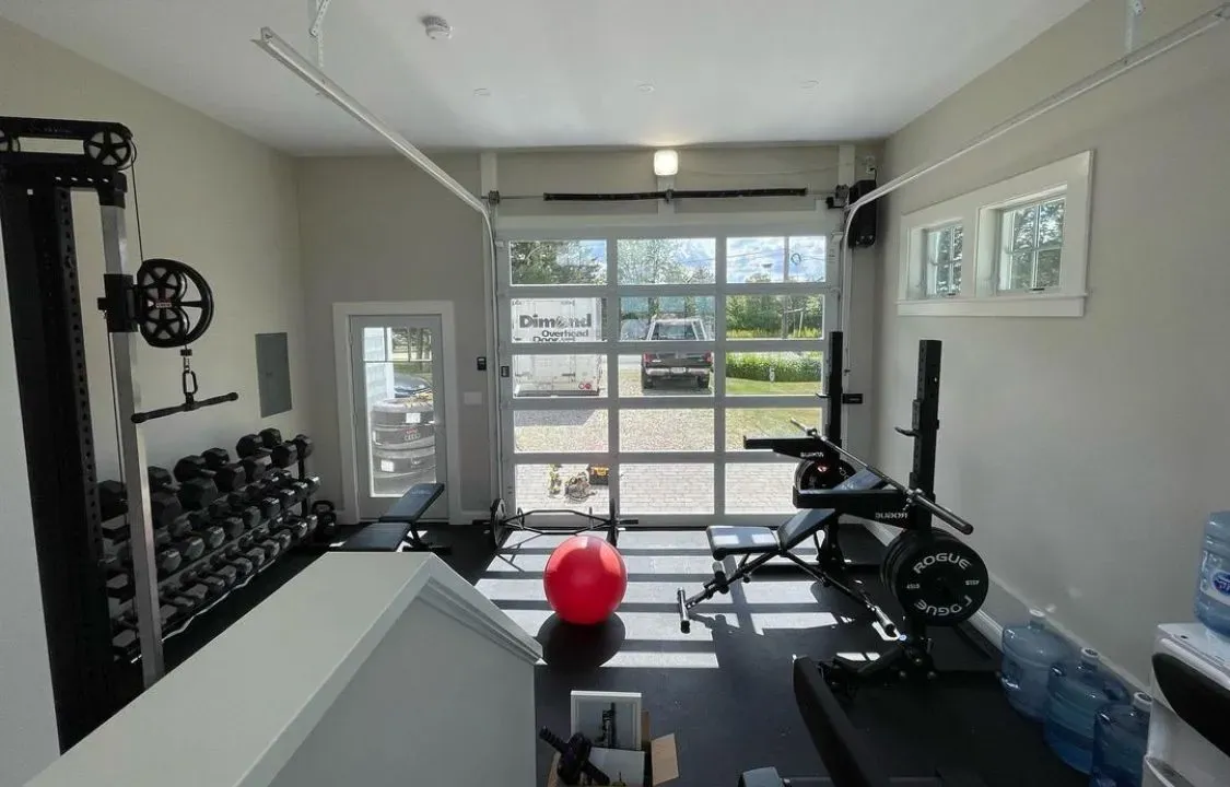 A gym in a garage with a red ball on the floor