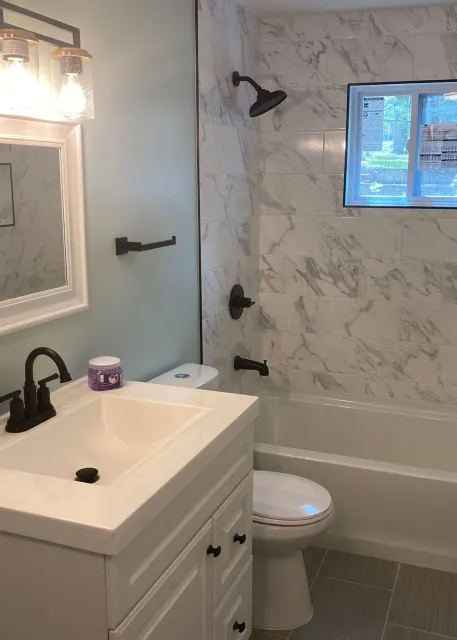 A bathroom with a sink , toilet , tub and mirror.