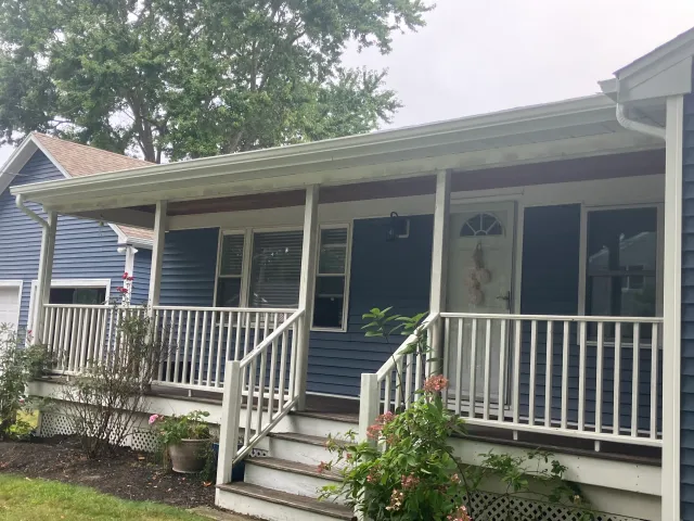 Front elevation of a West Warwick home with original worn white siding