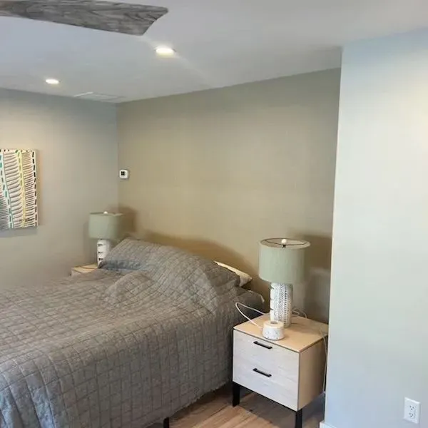 A bedroom with a bed , nightstand , lamps and a ceiling fan.