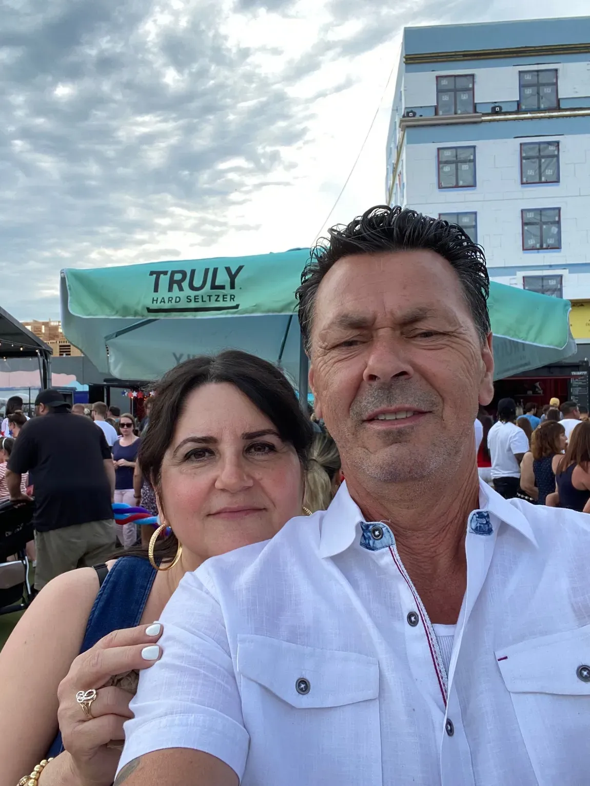 Two people taking a selfie outdoors in front of a TRULY booth and a building