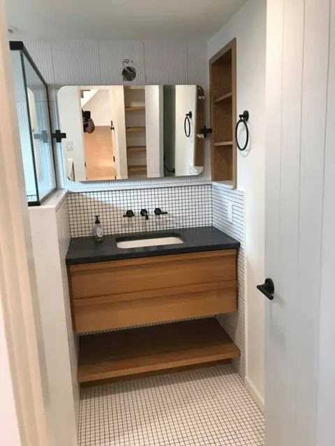Finished bathroom with tiled shower and custom vanity