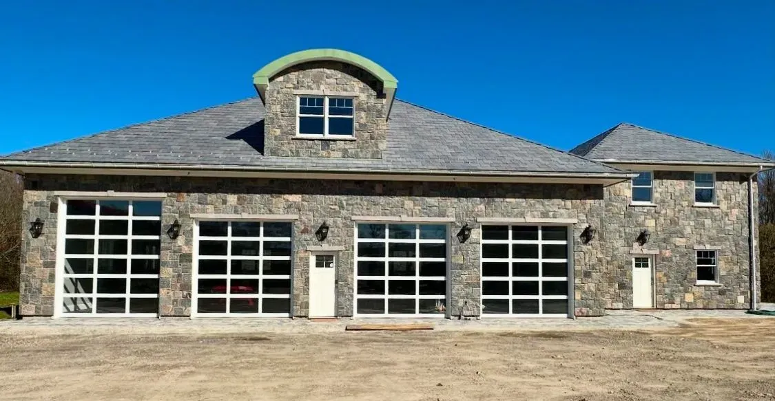 A large stone house with three garage doors