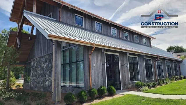 A large wooden building with a metal roof is under construction.