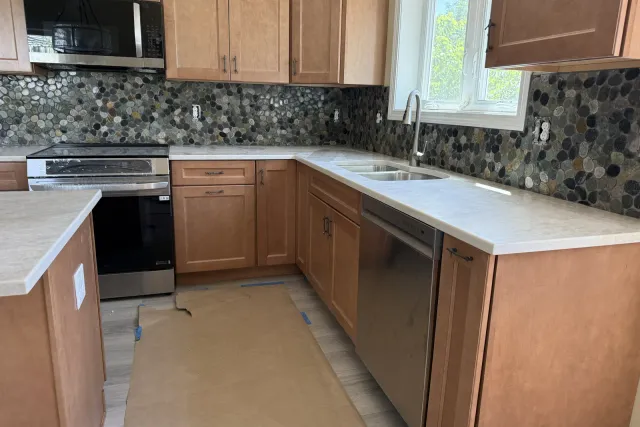 Pebble mosaic kitchen backsplash from counter to upper cabinets around the sink window by Dmtilellc in Plainville, CT