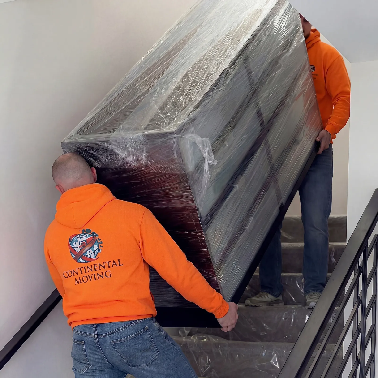 Movers carrying wrapped furniture upstairs during labor-only service
