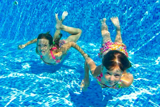 Kids playing underwater in a clean pool