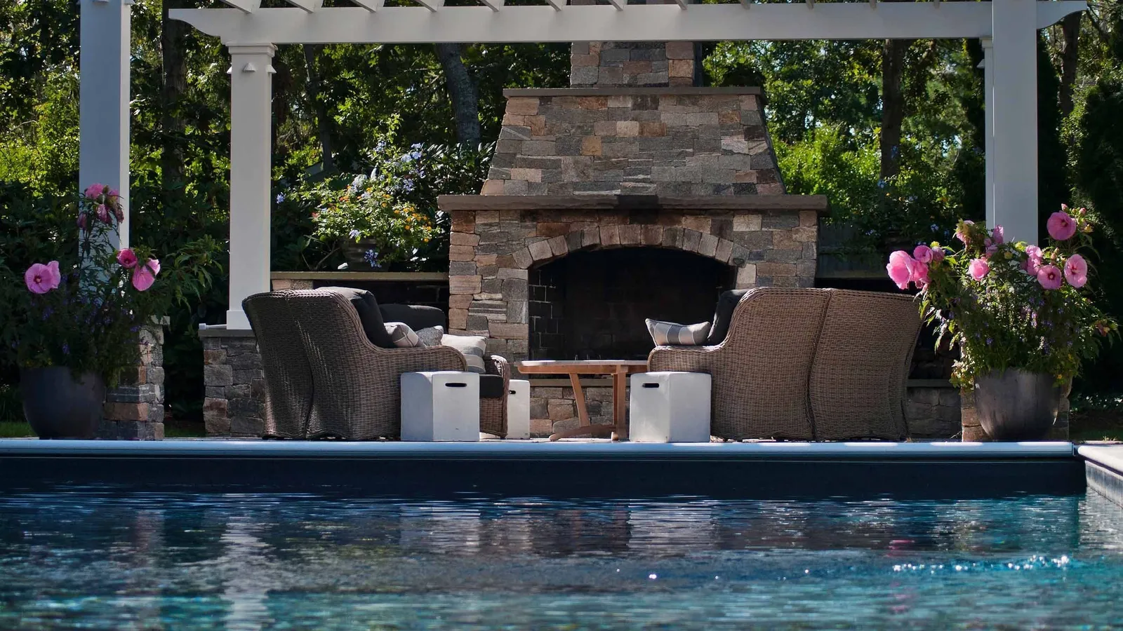 Outdoor fireplace in patio next to custom swimming pool