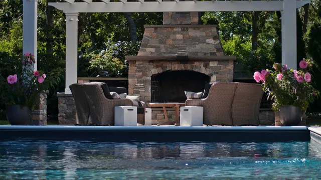 Outdoor fireplace in patio next to custom swimming pool
