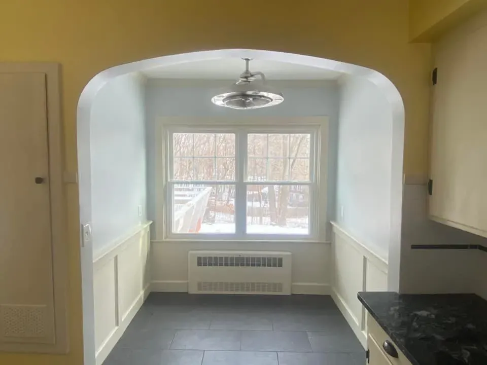 An empty kitchen with a ceiling fan and a window