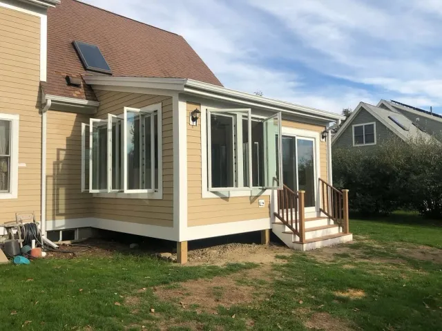 4 seasons addition to a back of a home, built on piers with large windows and staircase. hardwood floors, Hardie siding and asphalt shingles for the roof.