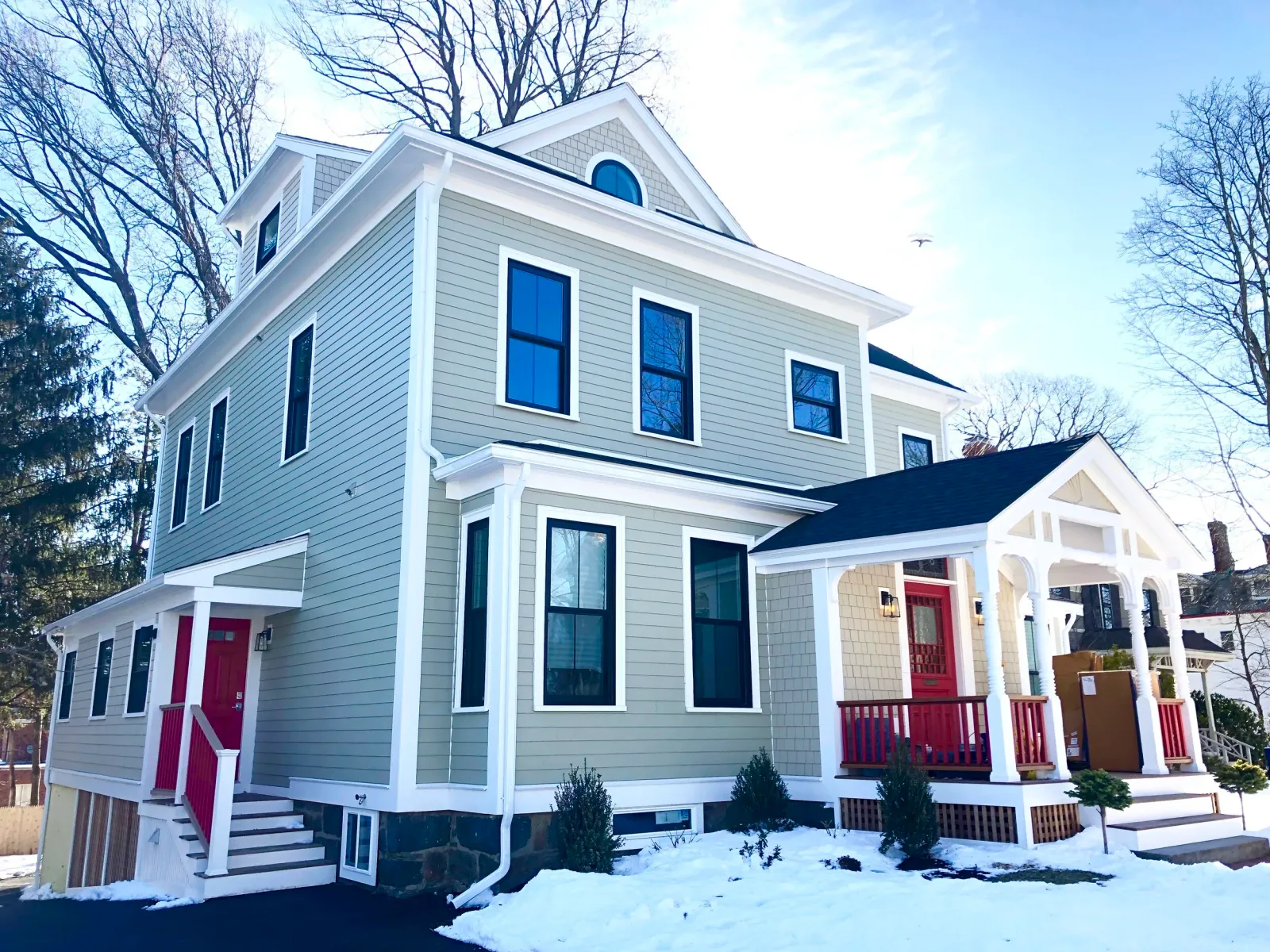 New siding, trim and windows are added to this historic home on Cape Cod with red doors and railings