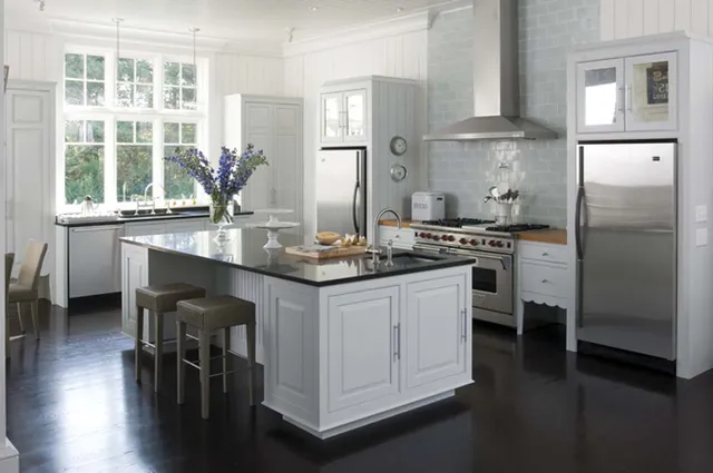 A kitchen with white cabinets and black counter tops.