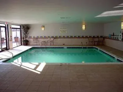 Indoor swimming pool with chairs along the wall and a glass door to the outside.