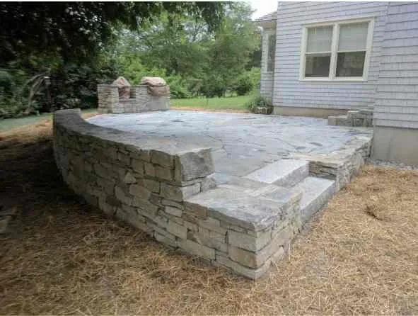 A stone patio with steps leading to the ground.