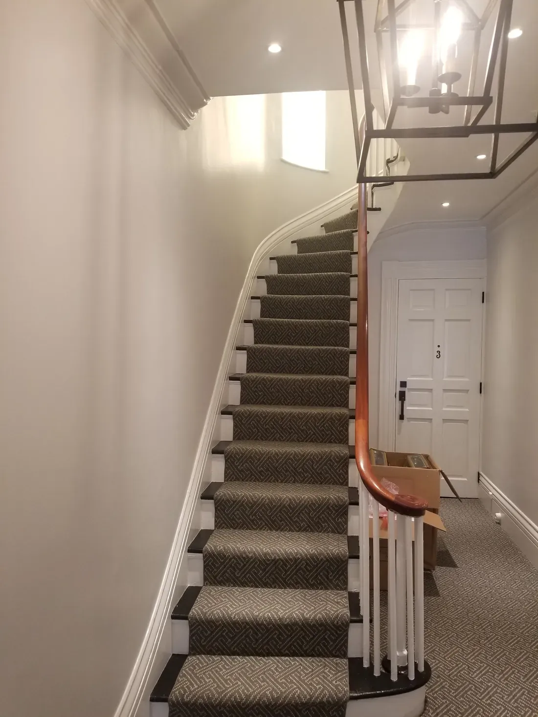 Stairway and hallway lit by recessed lighting and a hanging lantern fixture
