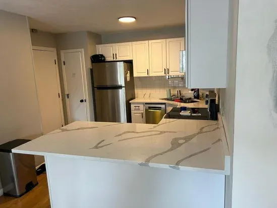 The completed kitchen peninsula showcasing the smooth surface and veining of the Calacatta Cosmos quartz.